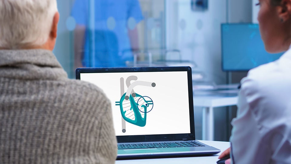 Operatore sanitario che mostra a un paziente un’immagine del cuore sullo schermo di un computer.